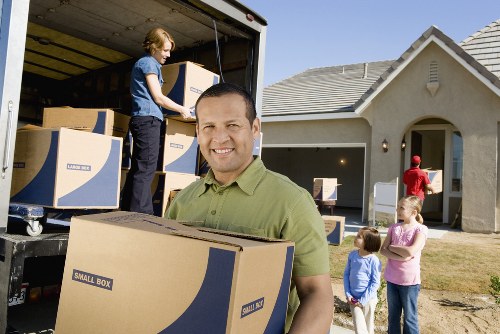 Movers carrying furniture through a residential property in House